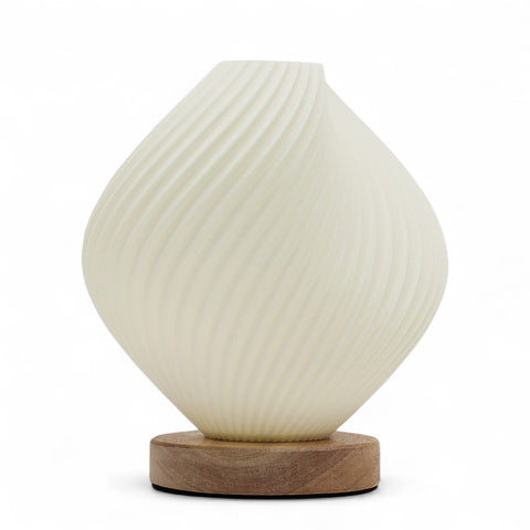 Front view of the cream twisted lamp glowing against a white background on its wooden base