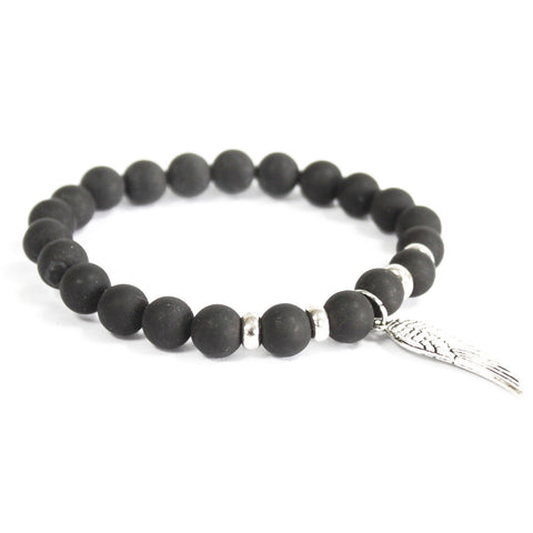 Black agate bracelet with round matte beads and a silver wing charm, shown alone on a white background