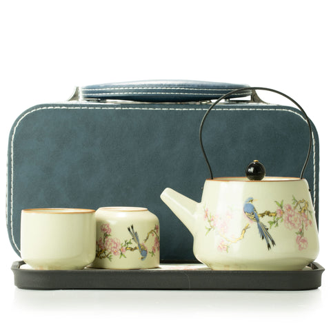 Full travel teapot set with two cups and teapot on a tray in front of the blue case