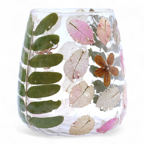 Close-up of the clear glass holder decorated with green leaves, pink petals and a brown flower