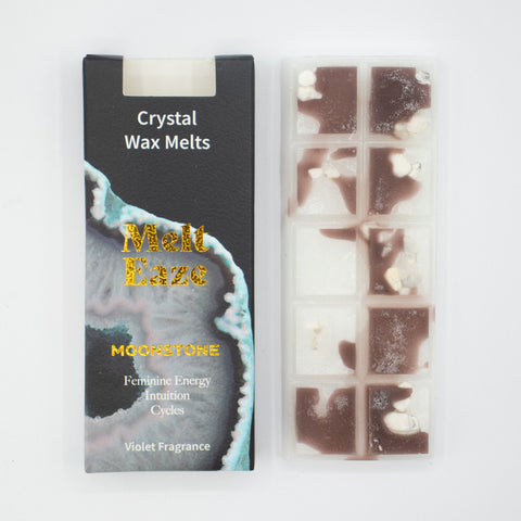 Moonstone wax melts in a clear tray beside the open black carton, showing white and violet sections