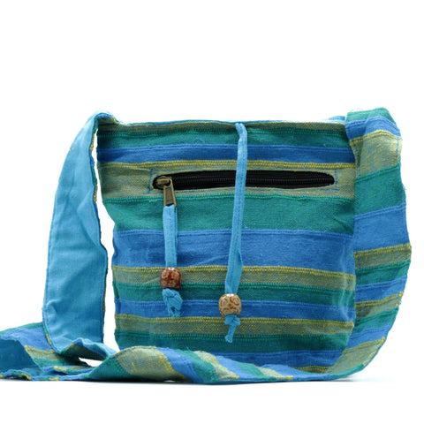 Nepal Sling Bag, Spring Meadows Green & Blue shown from the front with a black zip pocket and cord fasteners