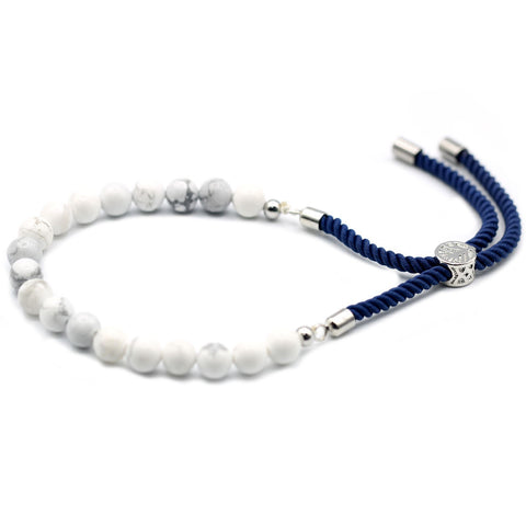 White gemstone beads and navy adjustable cord laid out on a plain white background