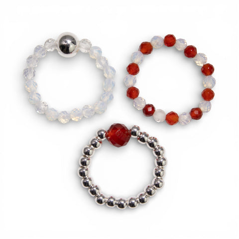 Three Blood Moon gemstone rings laid flat, showing pale, red and silver designs