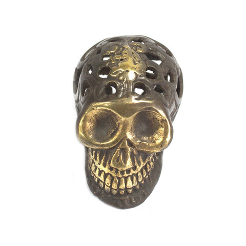 Brass skull viewed straight on against white, showing its gold-toned face and pierced crown