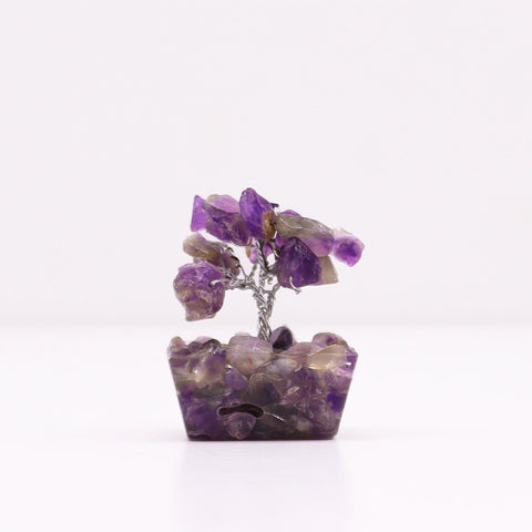 Amethyst gemstone tree viewed straight on against a plain pale background
