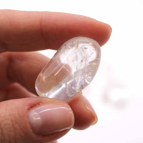 M Tumble Stones, Rock Crystal Grade A, a clear polished stone held between fingers in close-up