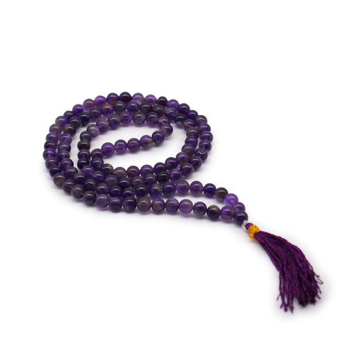 Amethyst mala arranged in a loose coil on white, showing its round purple beads and matching tassel