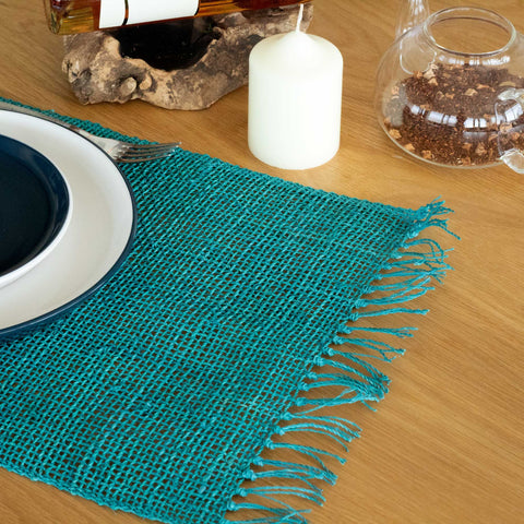 Seagrass Fringe Natural Placemat, Turquoise, shown close up on a wooden table with fringed edge