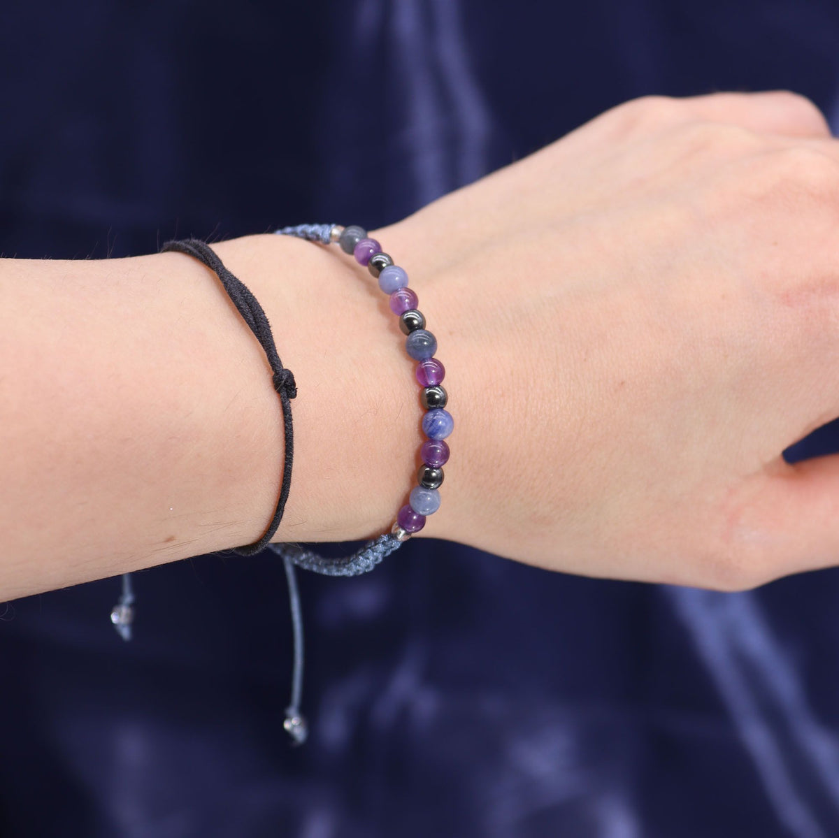 A beaded bracelet worn on a wrist against a dark blue background.