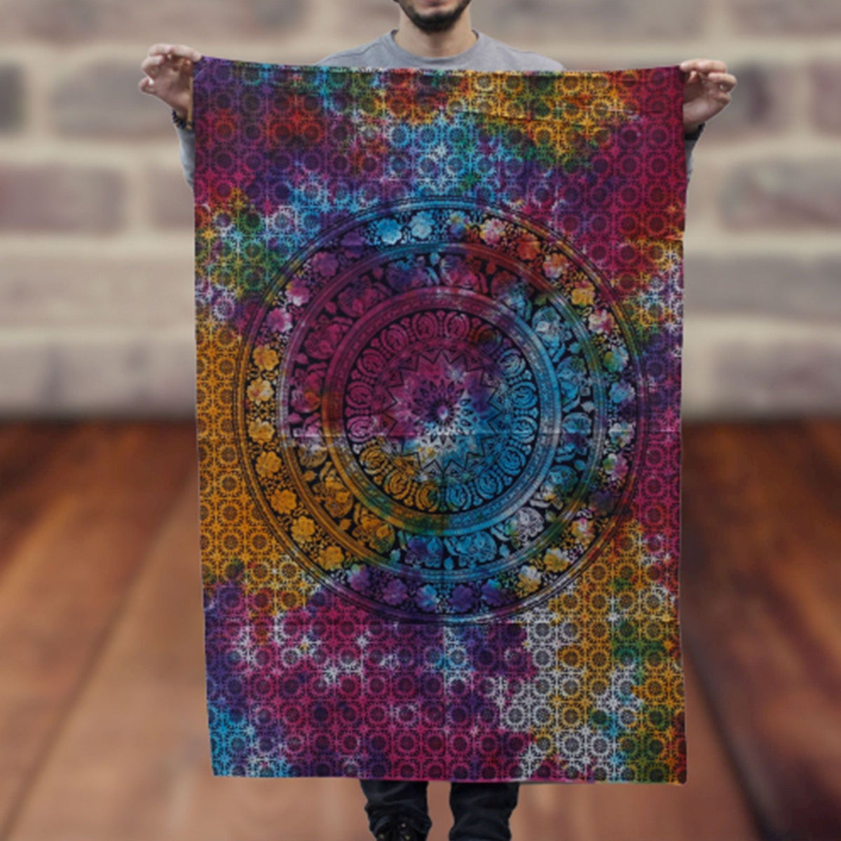 A person holds a colourful patterned wall hanging with a circular mandala design.