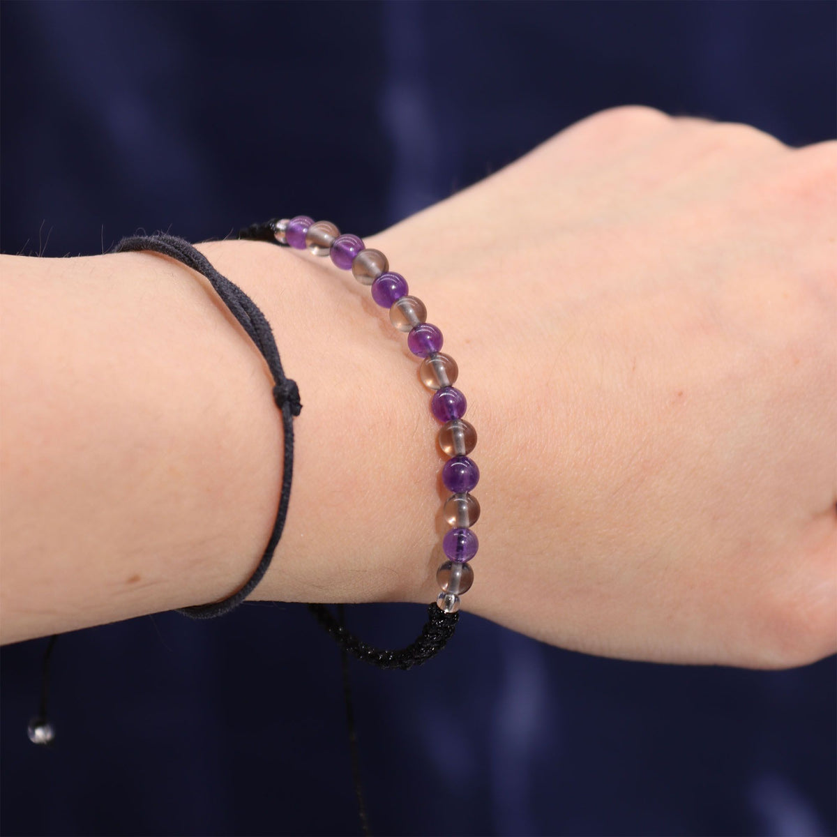 A wrist wearing a beaded bracelet against a dark background.