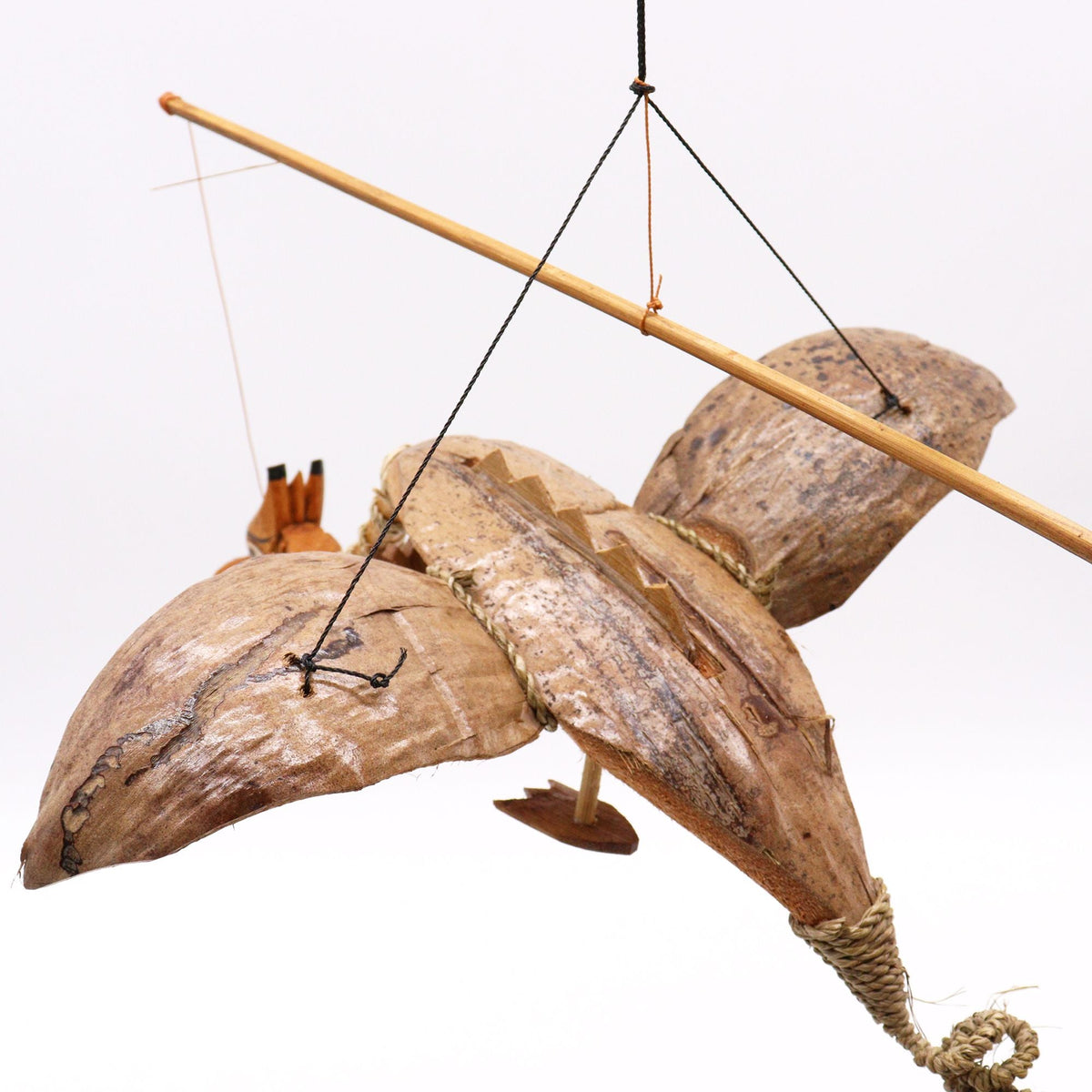 A hanging wooden dragon mobile with coconut shell pieces and black cords against a white background.
