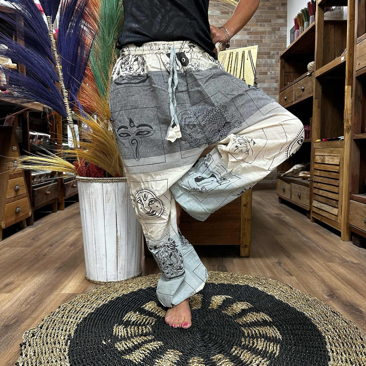 A person modelling loose grey and cream patterned trousers indoors.
