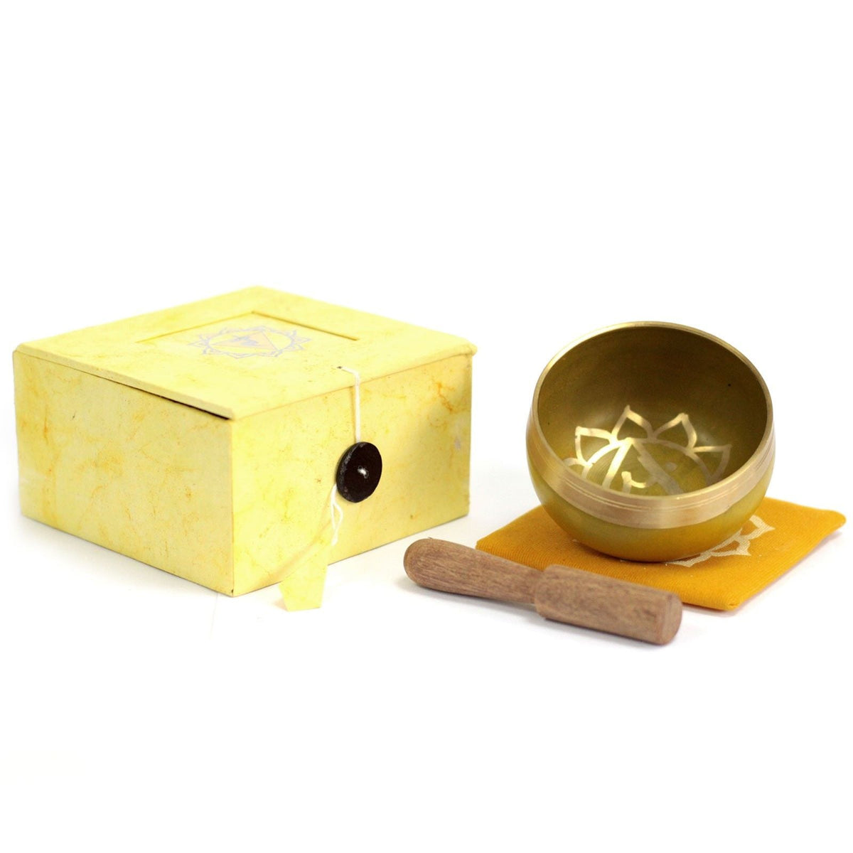Small brass singing bowl with a wooden mallet, yellow cloth and matching box on a white background.