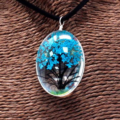 An oval pendant with a silver loop hanging on a woven brown surface.