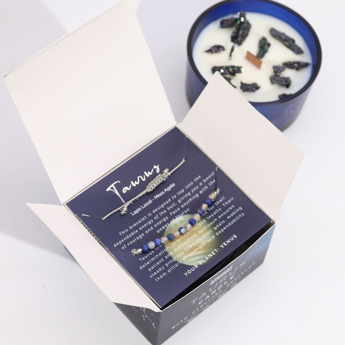Open box with a Taurus gemstone bracelet inside, beside a blue candle with stones on top