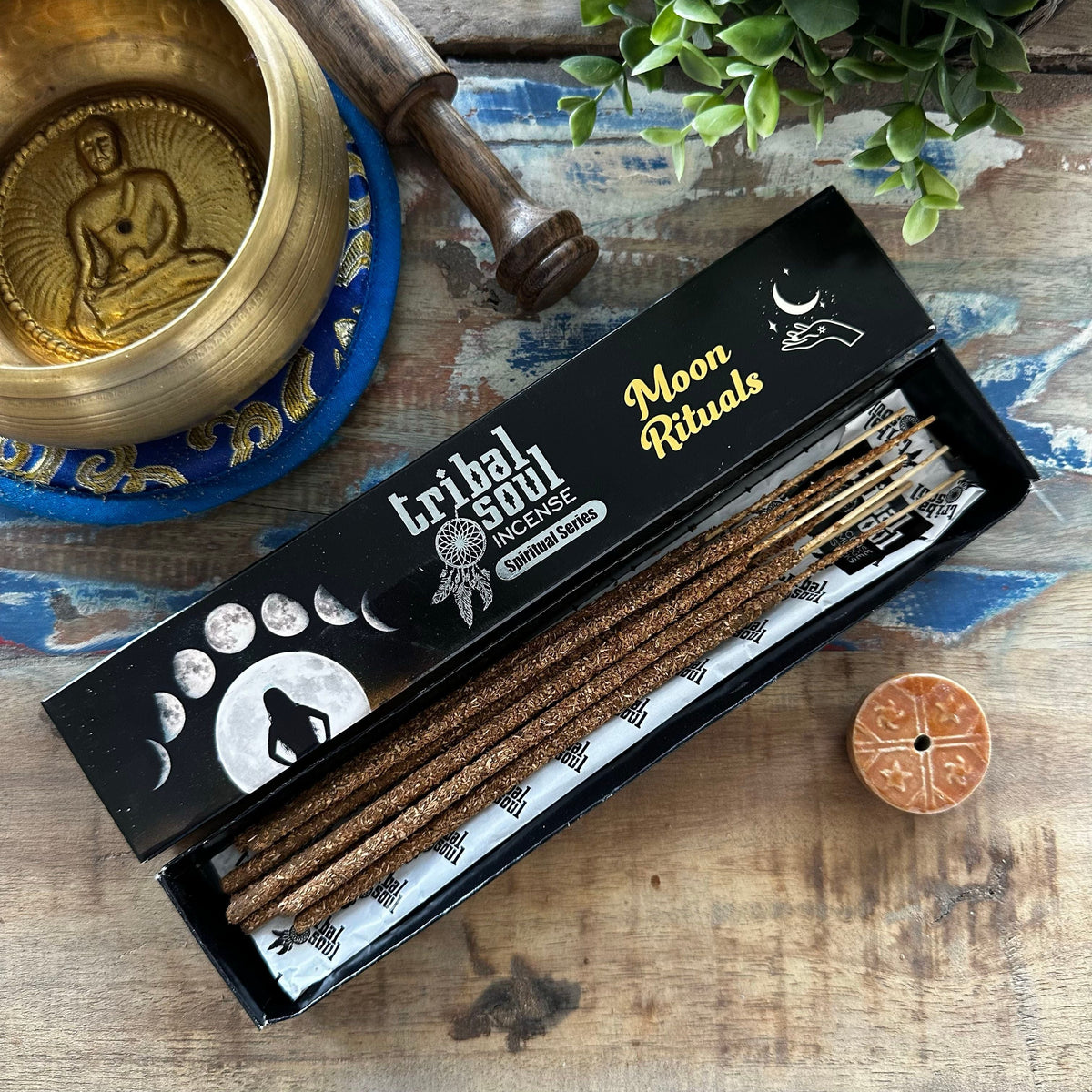 An open box of Moon Ritual incense sticks on a wooden surface beside a small round incense holder.