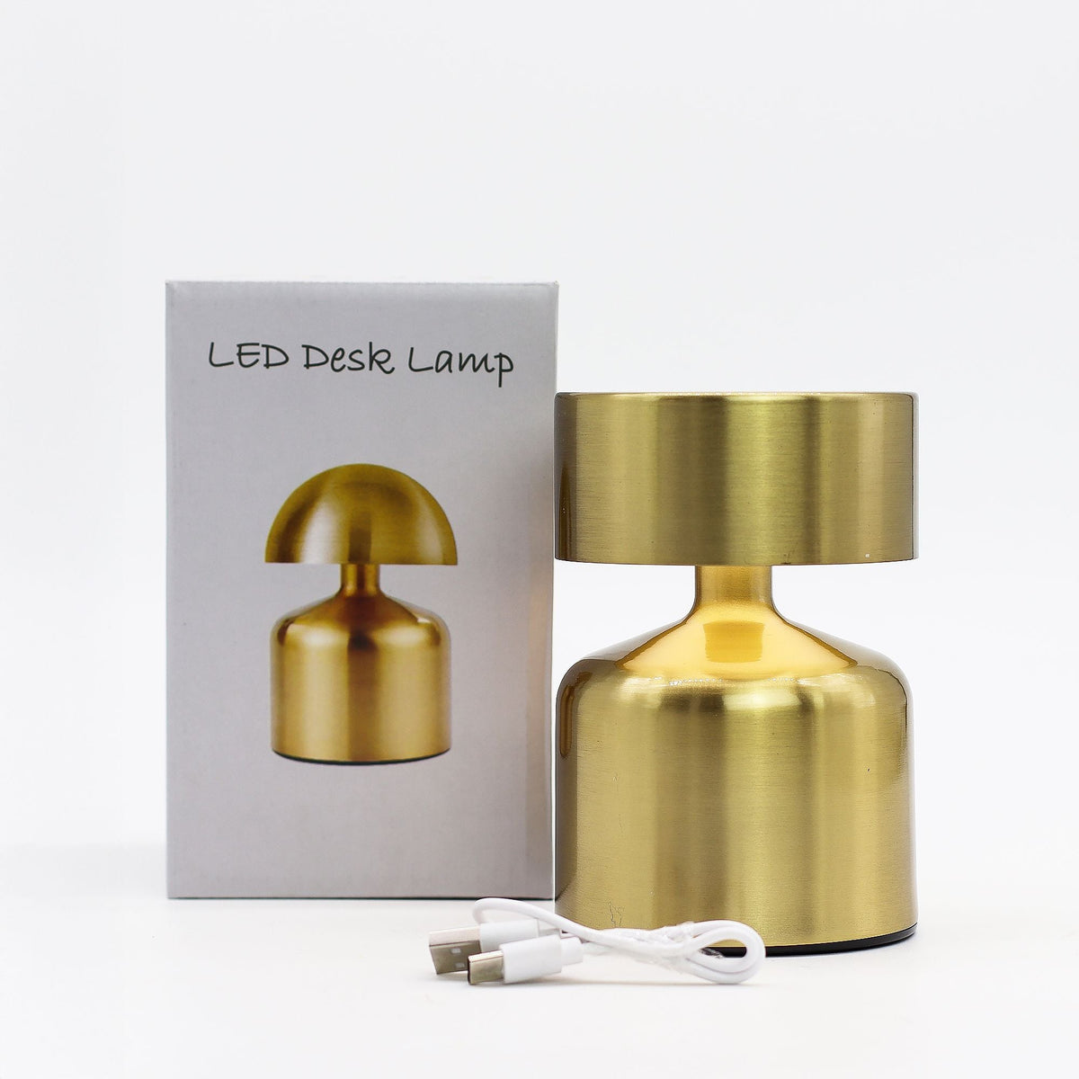 A gold desk lamp beside its box, with a white USB cable in front.