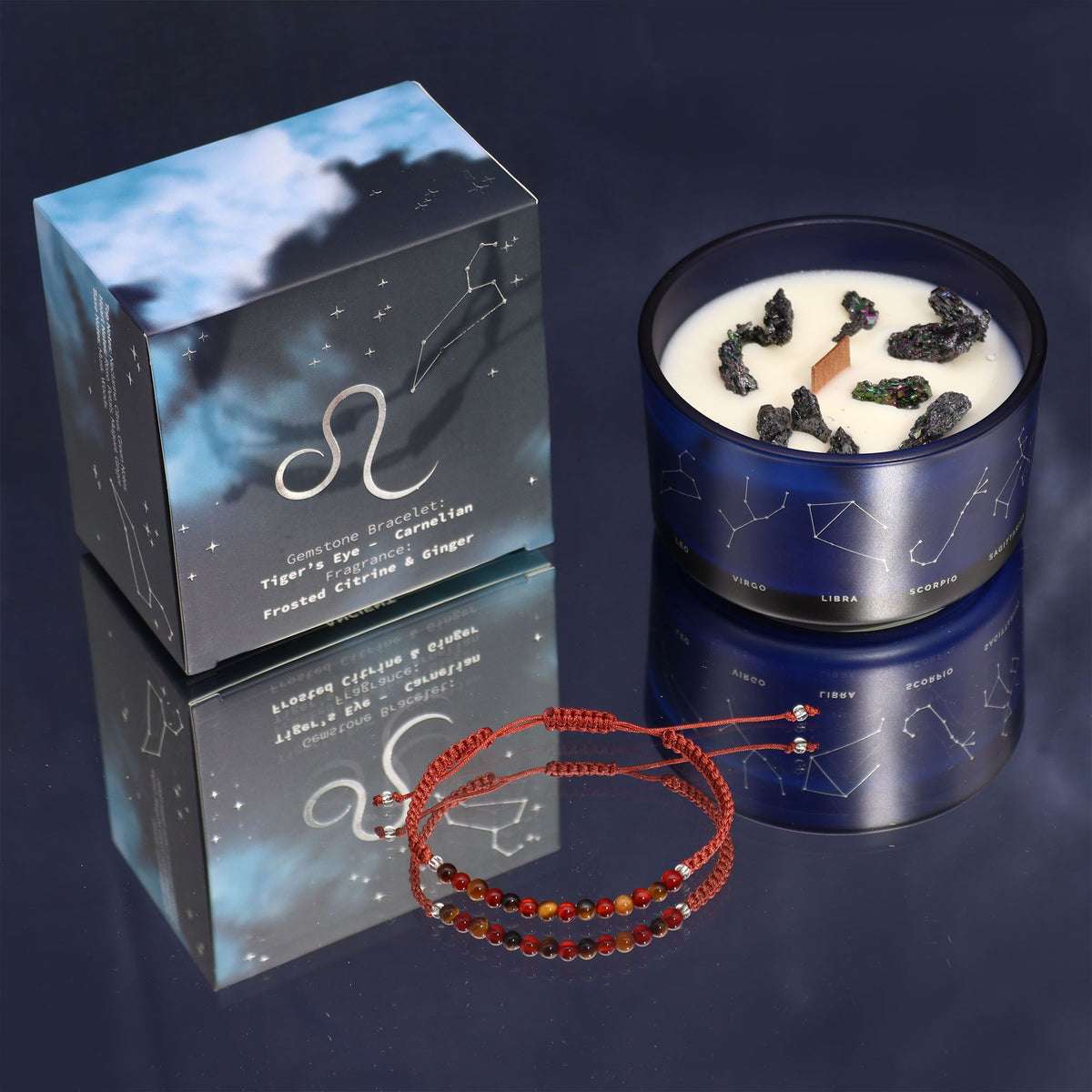A boxed candle, an open candle with stones on top, and a beaded bracelet on a dark surface.