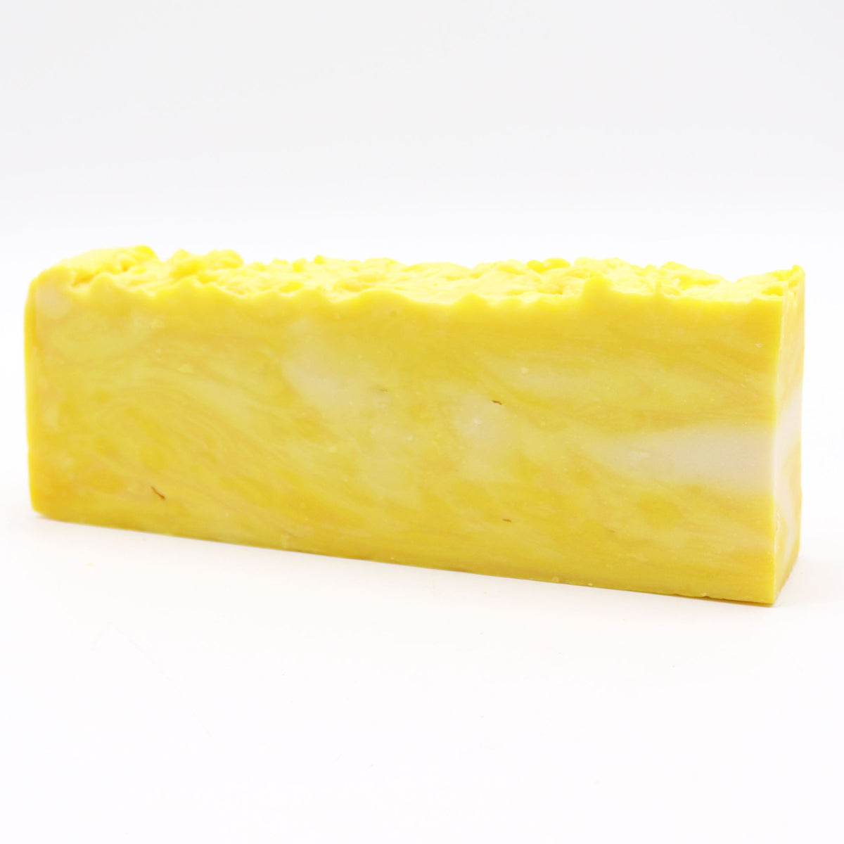 Yellow marbled lemon soap loaf shown whole from the front, with its textured top edge visible