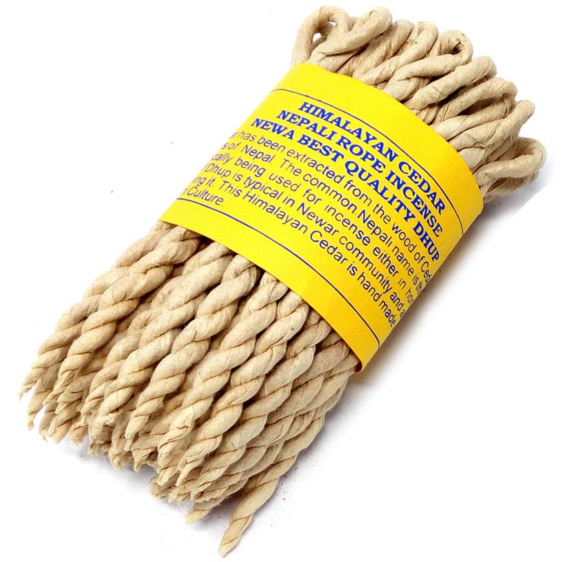 Close-up of pale twisted cedar incense ropes wrapped with a yellow label on a white background