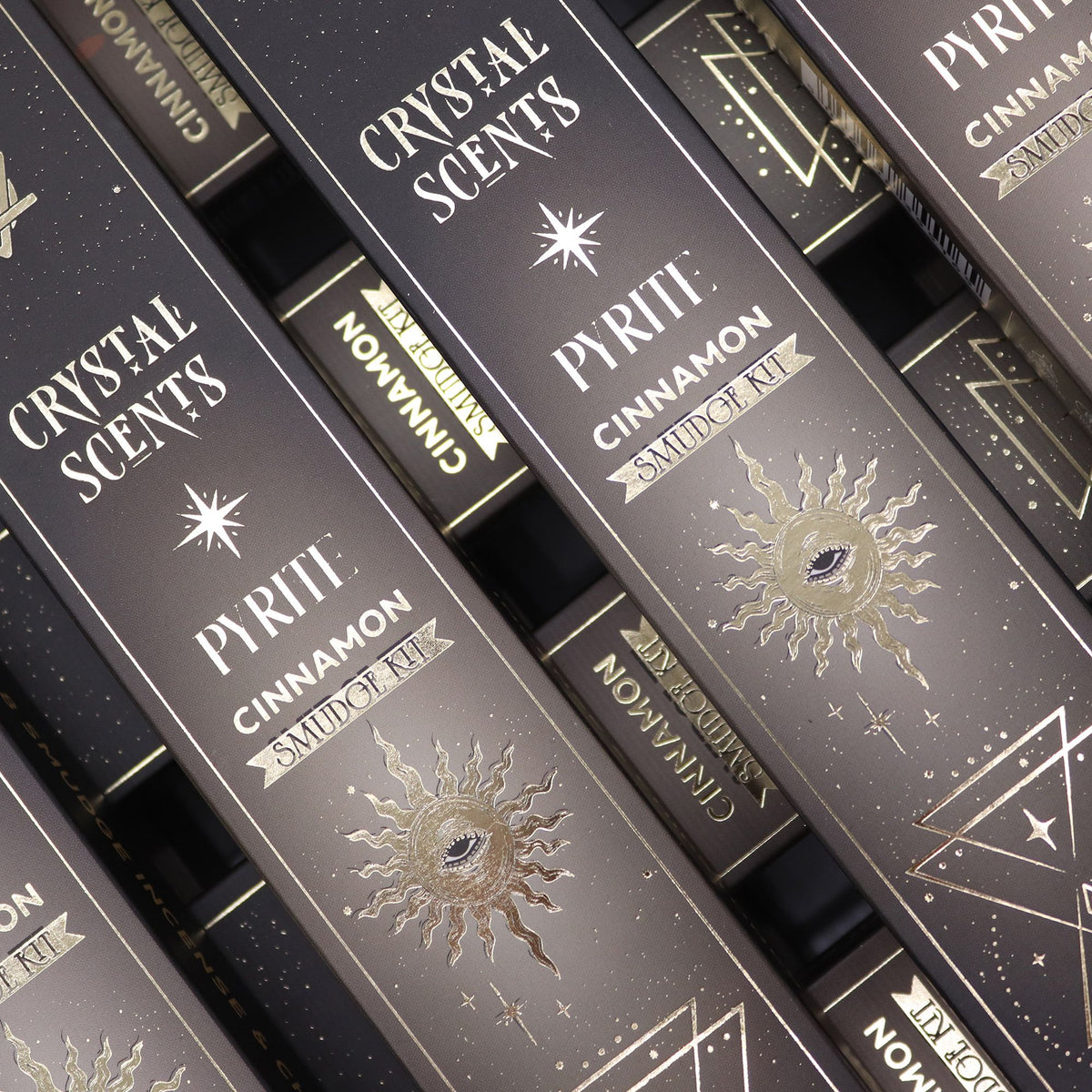 Pyrite Crystal Scents Smudge Incense, Cinnamon, close-up of dark boxes with gold sun designs