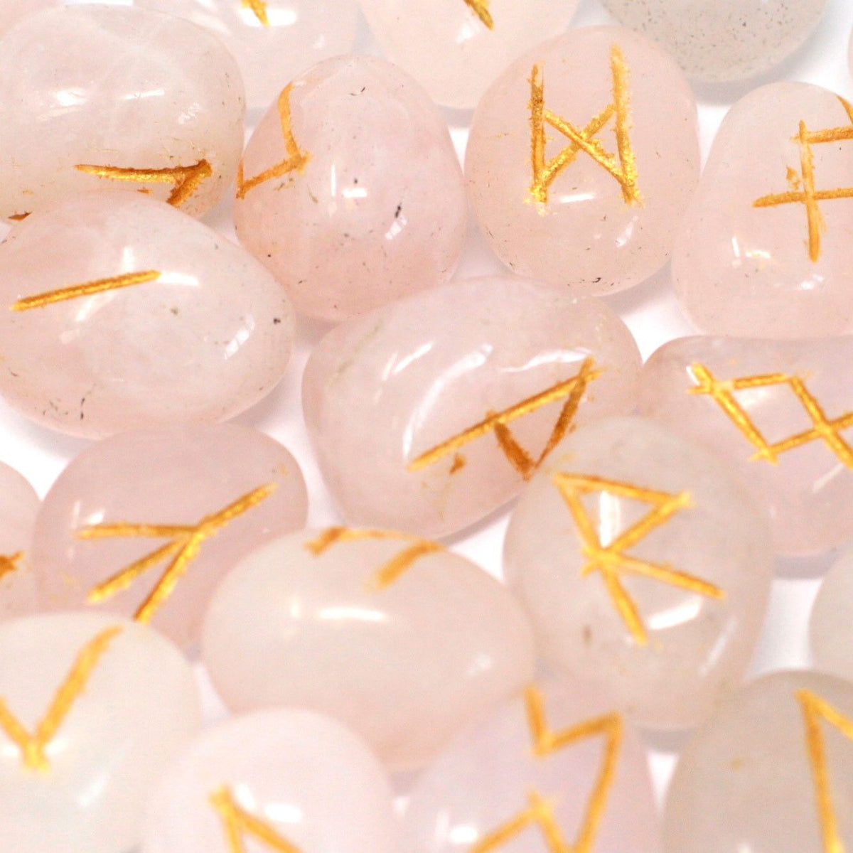 Runes Stone Set in Pouch, Rose Quartz, close-up of pale pink stones engraved with gold runes