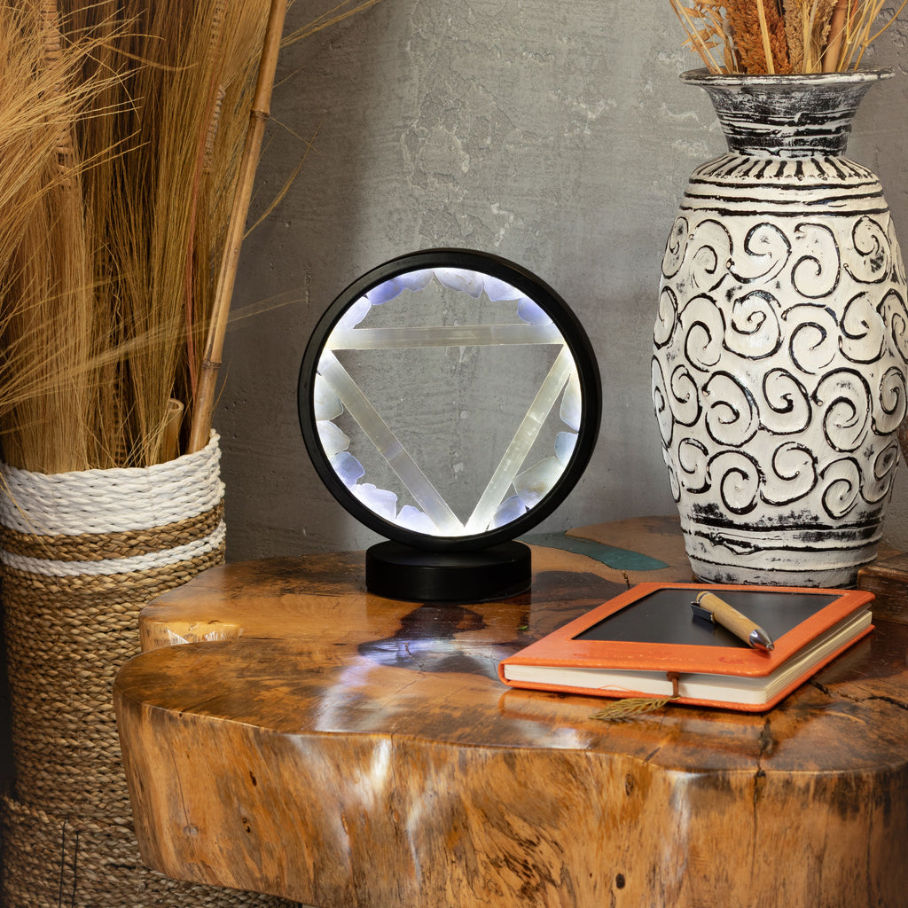 Lamp displayed on a table beside a vase and notebook