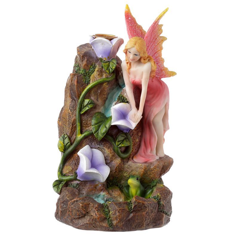 Front view of the fairy burner against white, with pink wings, purple flowers and a green vine on the rocks