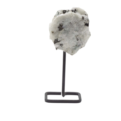 Rainbow moonstone on a black metal stand, front view of a pale rough stone with dark inclusions