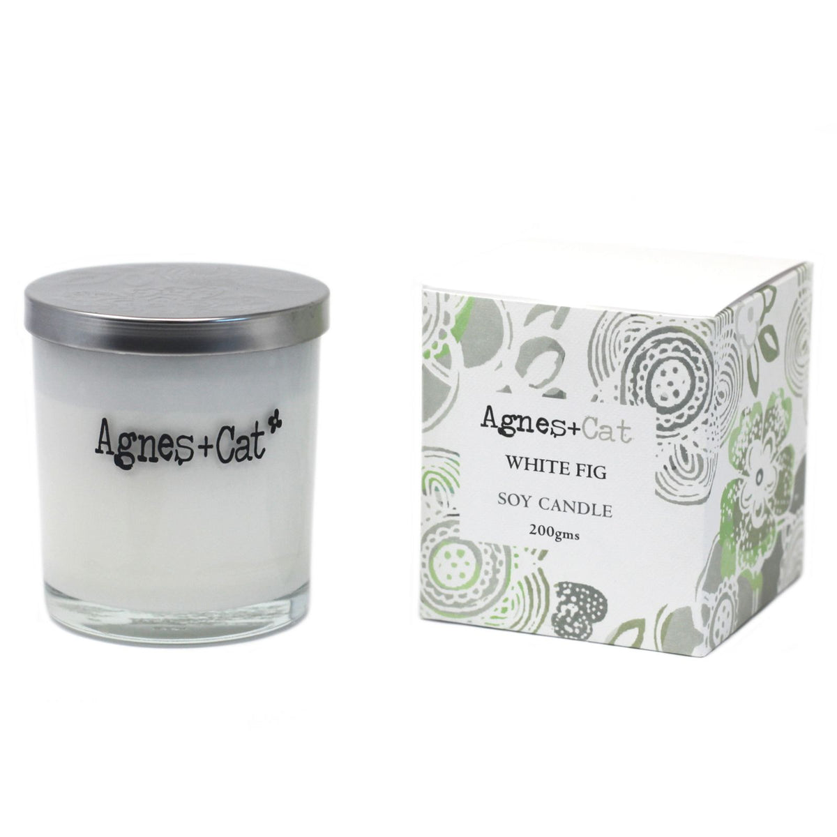 Agnes + Cat White Fig candle in a silver-lidded glass jar beside its patterned box on white