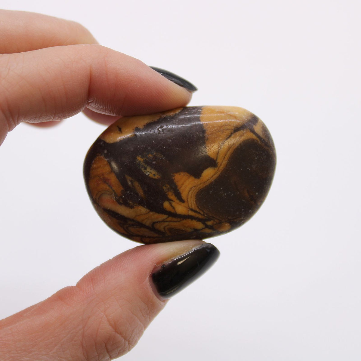 Large African Tumble Stones, Picture Nguni, a rounded brown and ochre patterned stone held between fingers