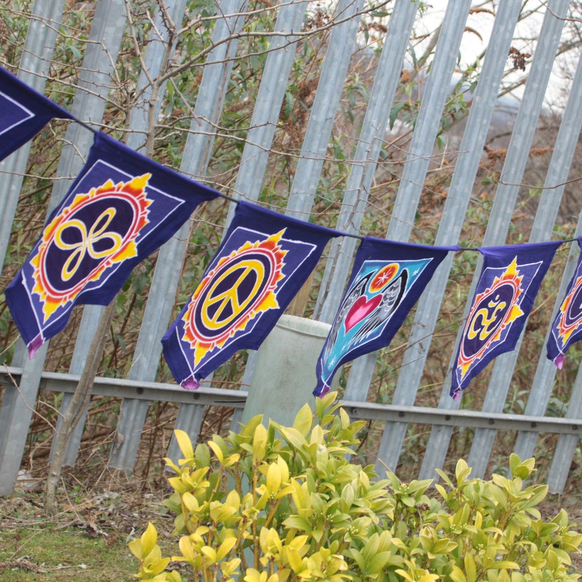 7 Flags Banner, Love in the Center, navy flags with colourful symbols strung outdoors among shrubs