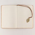 Open notebook showing lined pages and its leaf bookmark