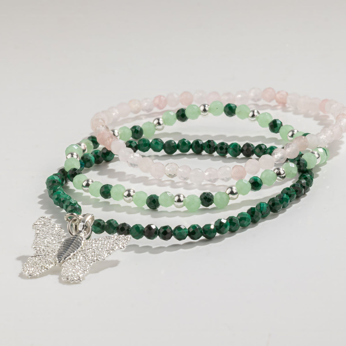 Three pink and green bracelets arranged in a stack