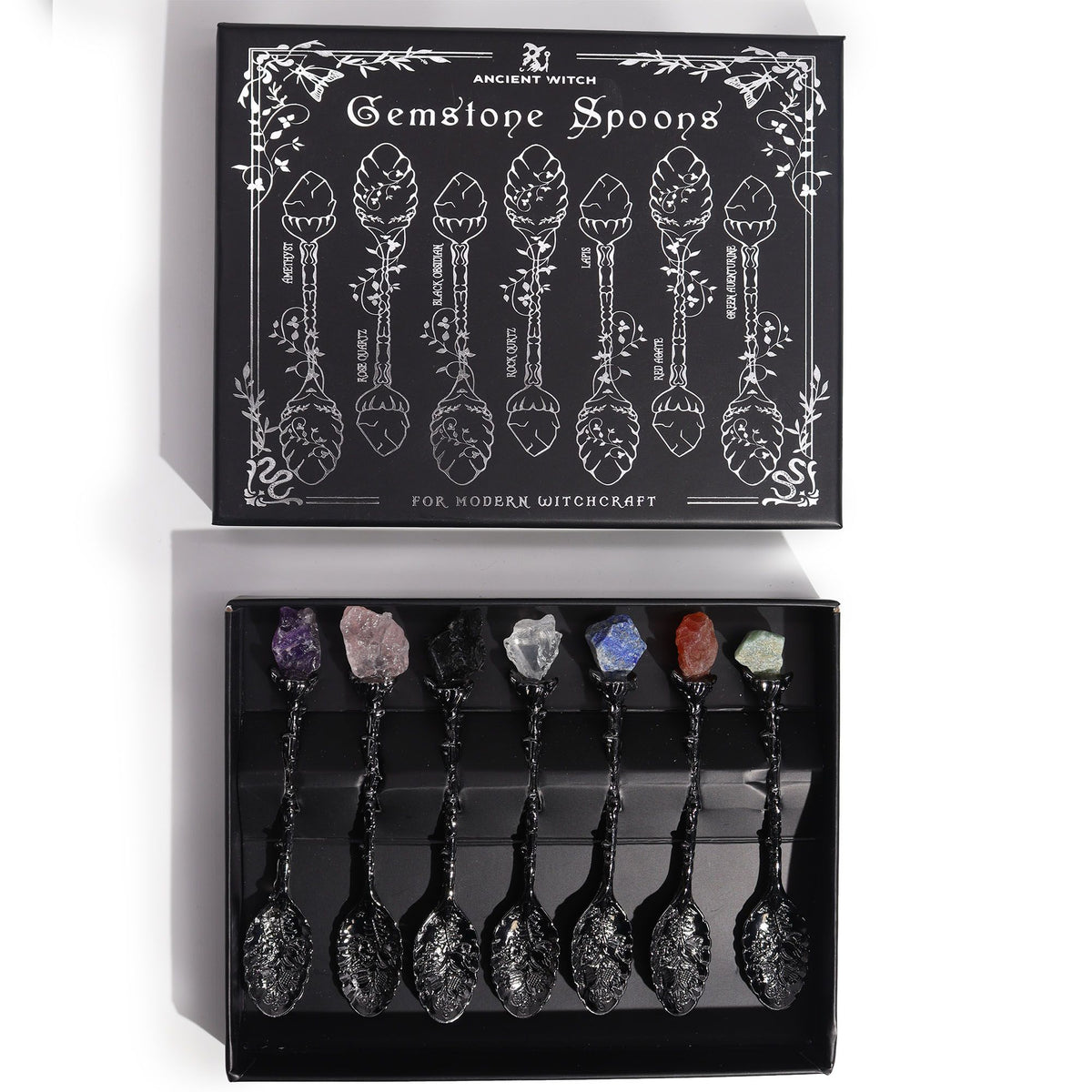 Dark silver crystal spoons arranged in an open black box beneath its illustrated lid, viewed from above