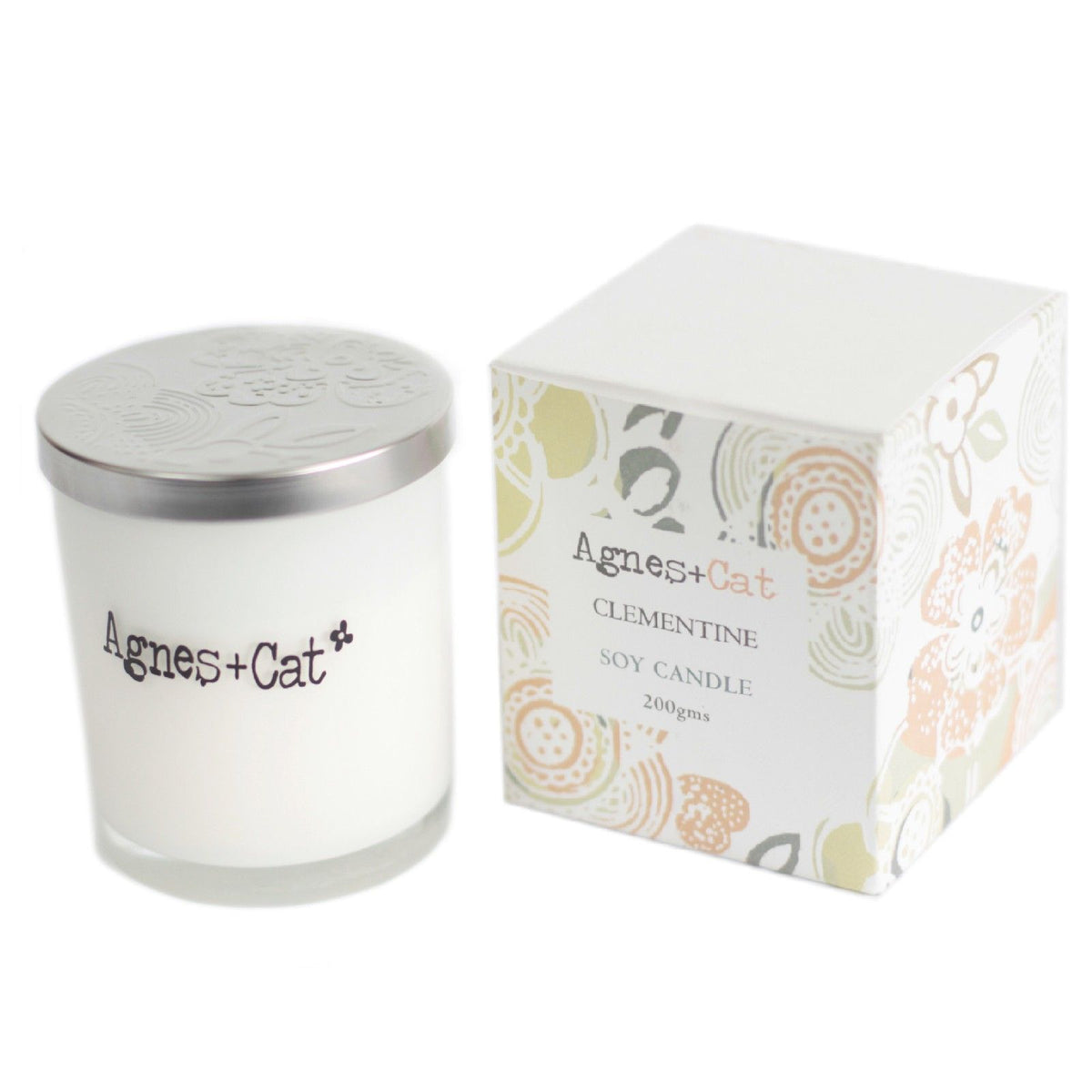Clementine candle with a silver lid beside its patterned box on a white background