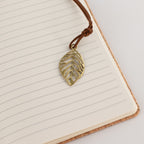 Leaf-shaped bookmark resting on the lined notebook pages