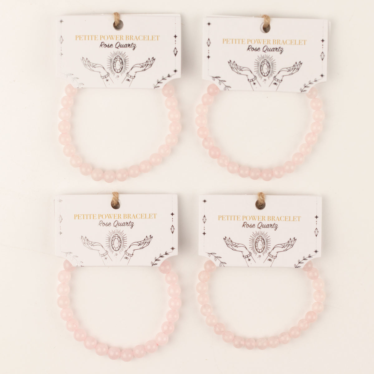 Four rose quartz bracelets displayed on illustrated cards