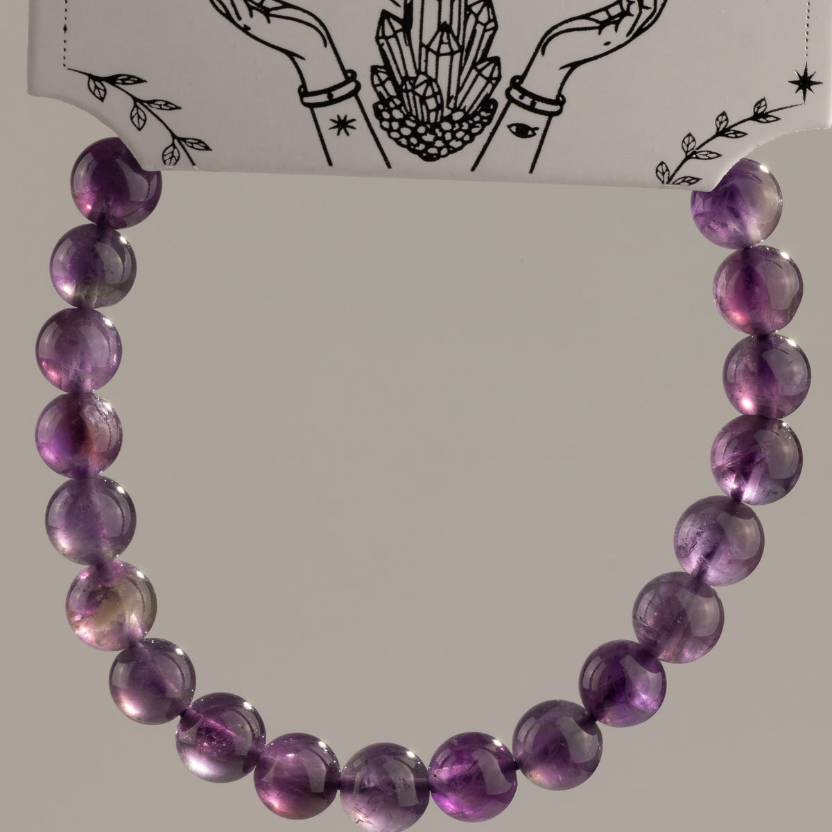 Amethyst bracelet arranged in a loop beneath its presentation card