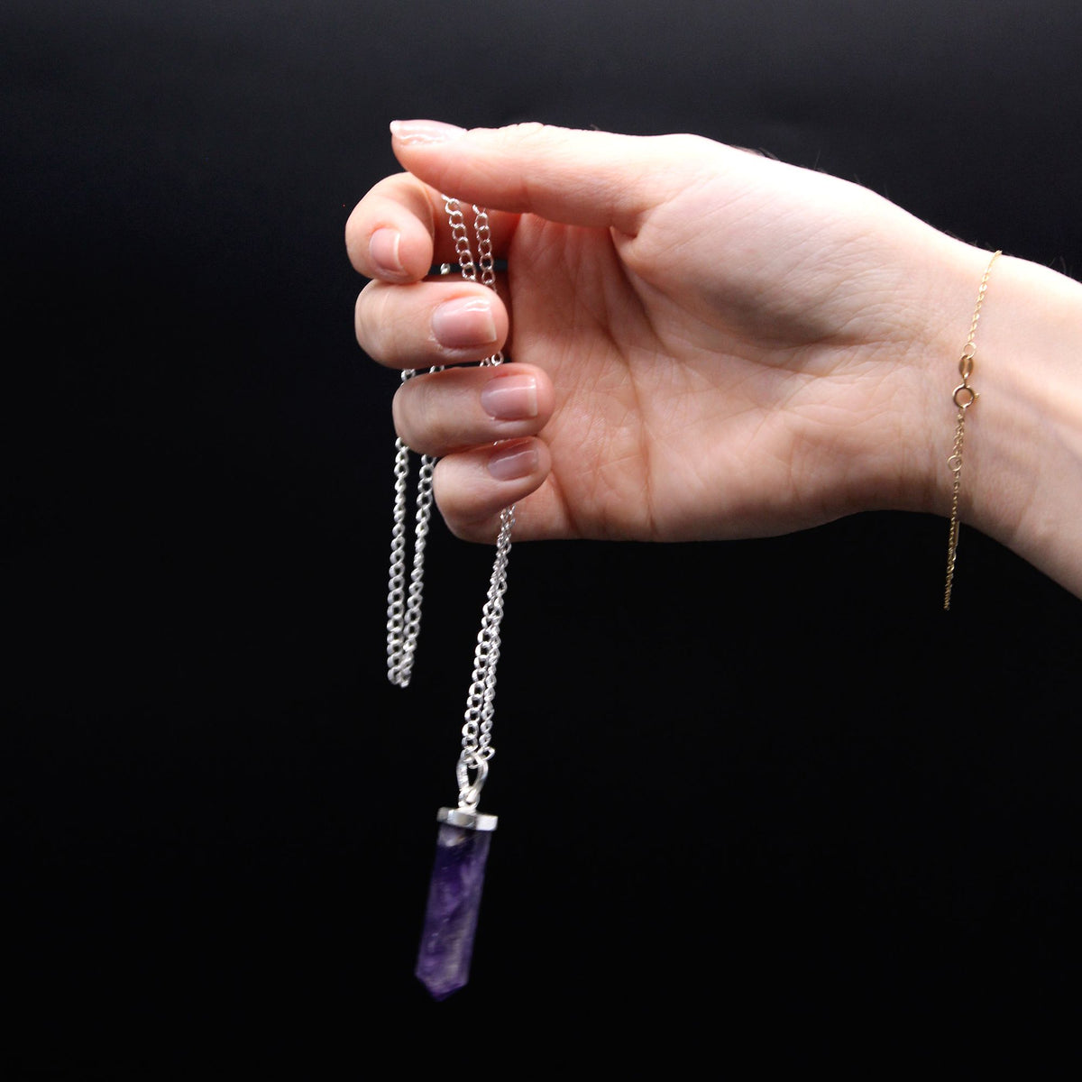 Gemstone Classic Point Pendant, Rock Quartz, purple point on a silver chain held against a black background