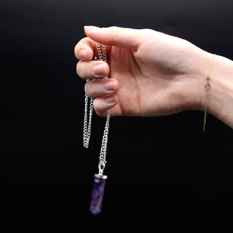 Gemstone Classic Point Pendant, Rock Quartz, purple point on a silver chain held against a black background
