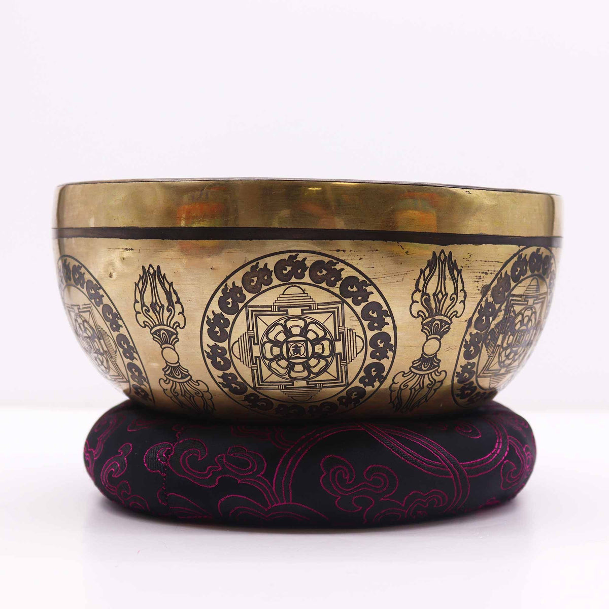 Hoop Cushion 18cm shown beneath a decorated brass singing bowl, black fabric with red pattern