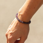 Purple amethyst beads worn around a wrist in sunlight