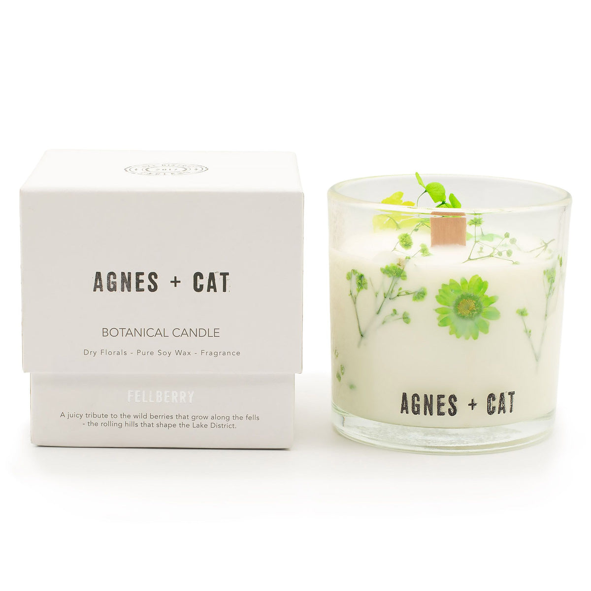 Fellberry candle in a clear glass with green botanicals, beside its white box