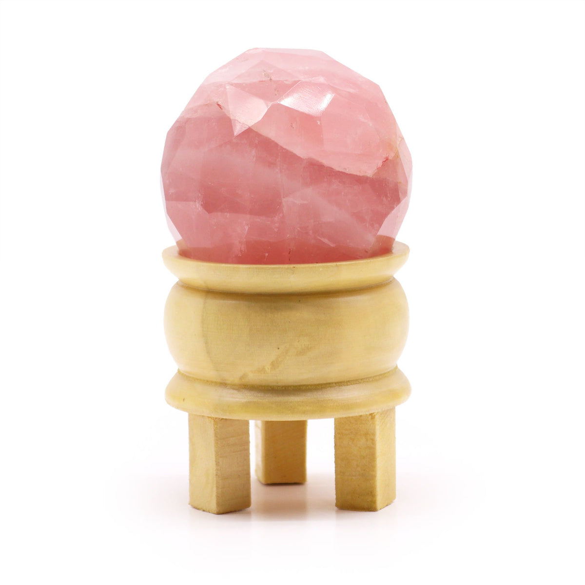 Faceted pink ball displayed on a light wooden stand