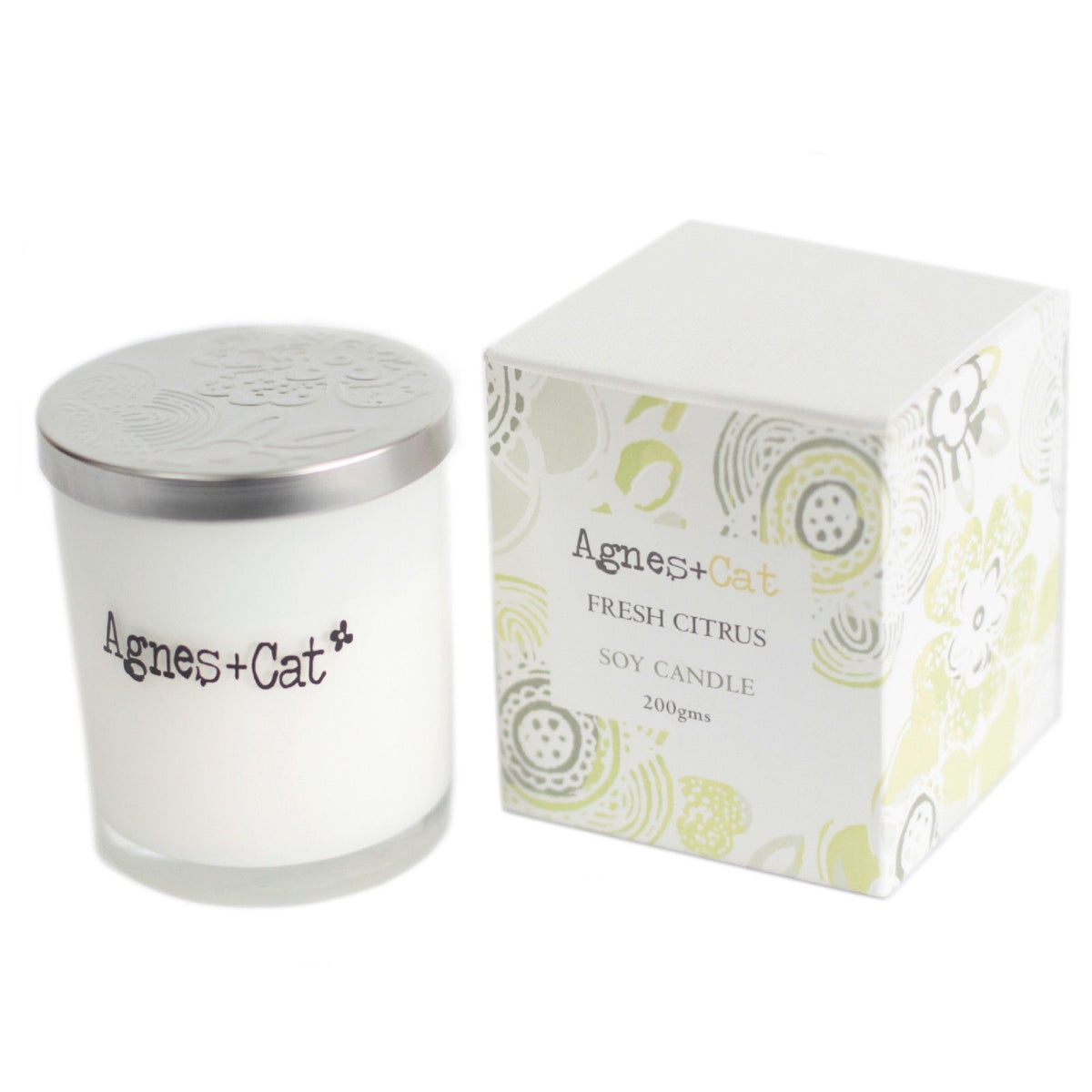 Agnes + Cat Votive Candle, Fresh Citrus, white candle with silver lid beside its patterned box