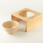 PAW cream ceramic pet bowl beside its light wood stand