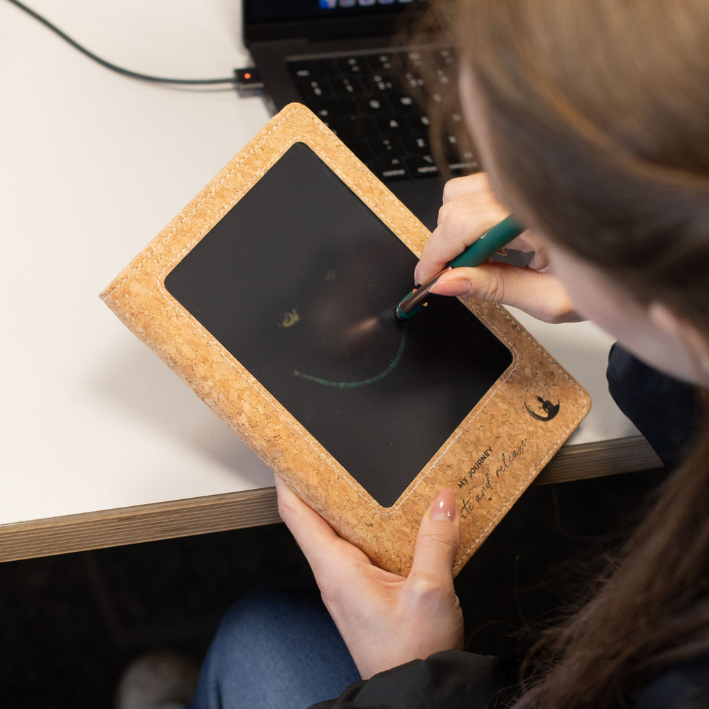 A person writing on a notebook’s LCD screen